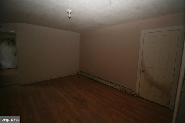 bonus room featuring dark wood-type flooring, a textured ceiling, and a baseboard heating unit