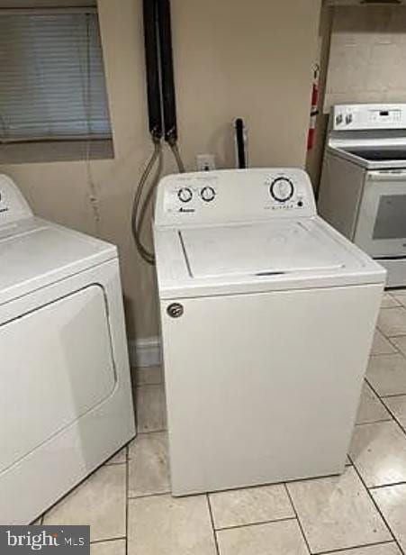 laundry room featuring washing machine and dryer and light tile patterned flooring