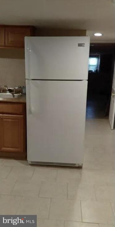 kitchen with white fridge, light tile patterned floors, and sink