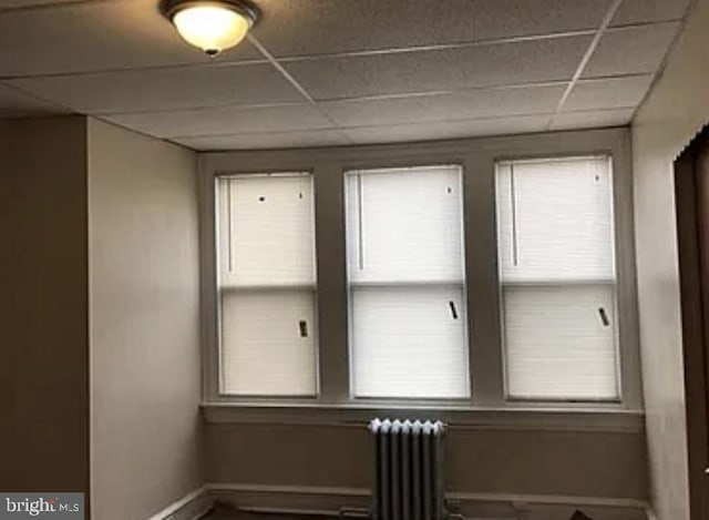 spare room featuring radiator heating unit and a drop ceiling