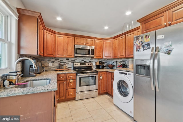 kitchen with sink, plenty of natural light, stainless steel appliances, and washer / dryer