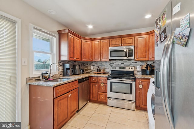 kitchen featuring sink, light tile patterned floors, tasteful backsplash, light stone counters, and stainless steel appliances