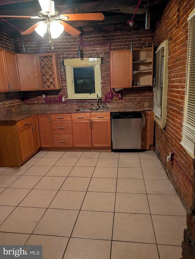 kitchen with dishwasher, light tile patterned floors, sink, and brick wall