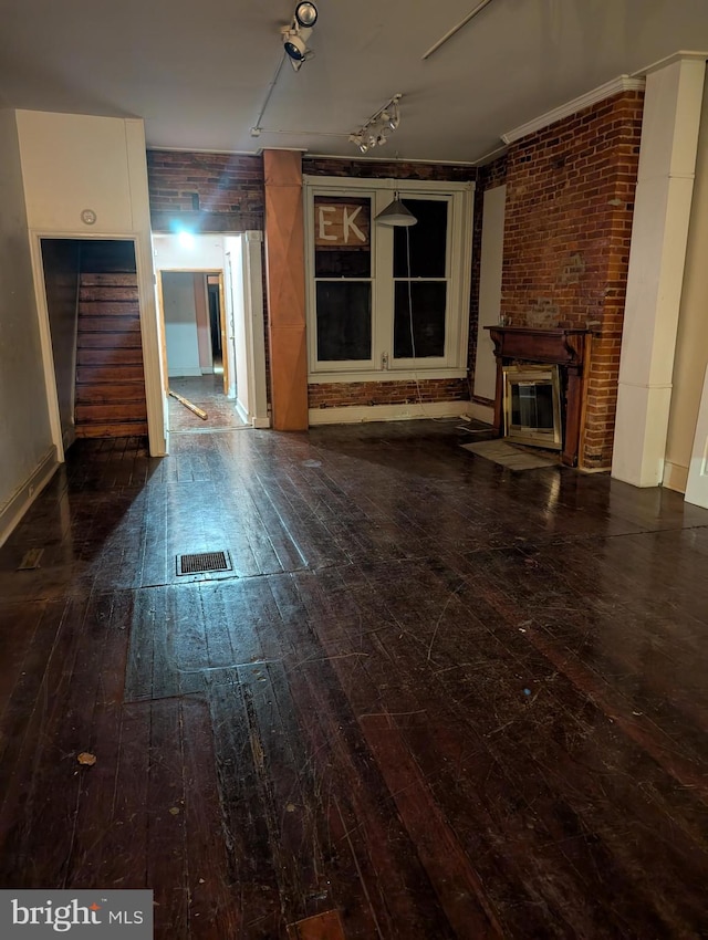 unfurnished living room featuring dark hardwood / wood-style flooring, a fireplace, and brick wall