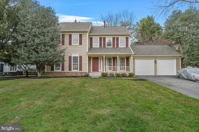 colonial home with covered porch, a garage, and a front yard