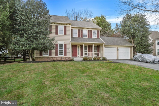 colonial home featuring a porch, a garage, and a front yard