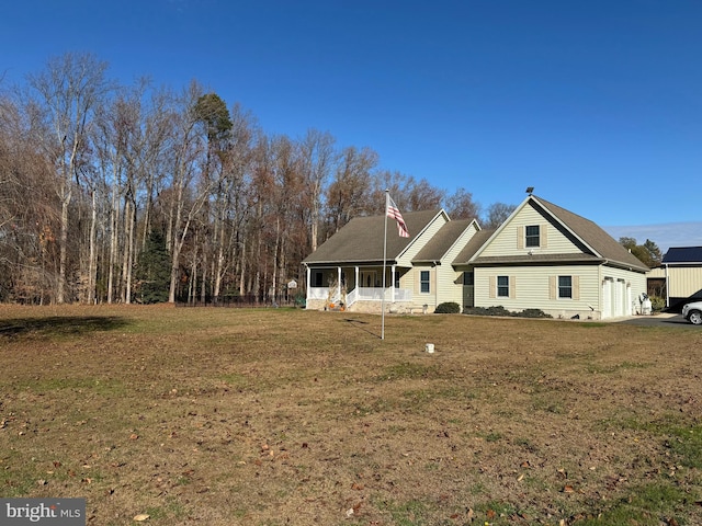 rear view of house featuring covered porch and a lawn