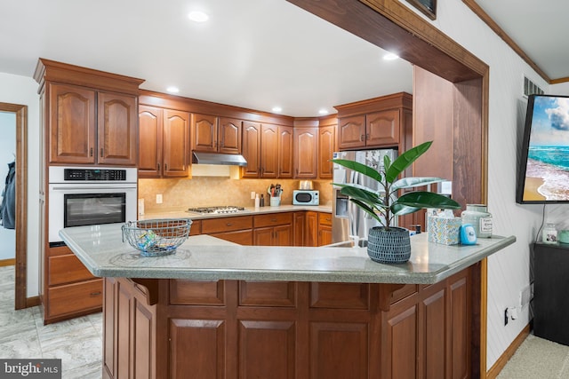 kitchen with backsplash, kitchen peninsula, ornamental molding, and stainless steel appliances