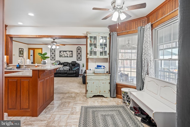 kitchen with ceiling fan, kitchen peninsula, sink, and light carpet