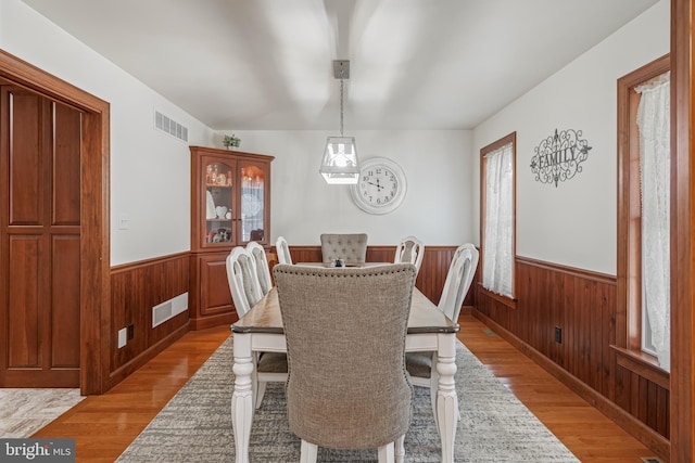 dining space featuring wood walls and light wood-type flooring