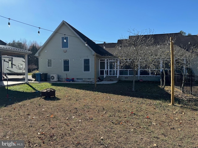 rear view of house featuring a lawn, ac unit, and a fire pit