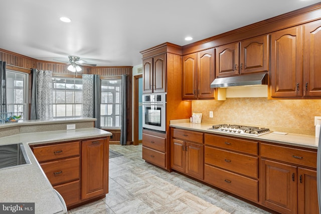 1060 Edwardsville Rd, Felton, DE 19943 - kitchen with stainless steel appliances, under cabinet range hood, light countertops, brown cabinetry, and a ceiling fan