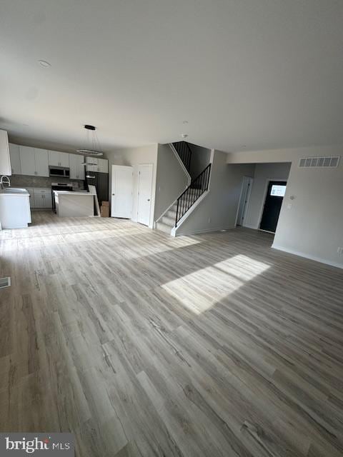 unfurnished living room with sink and light hardwood / wood-style floors