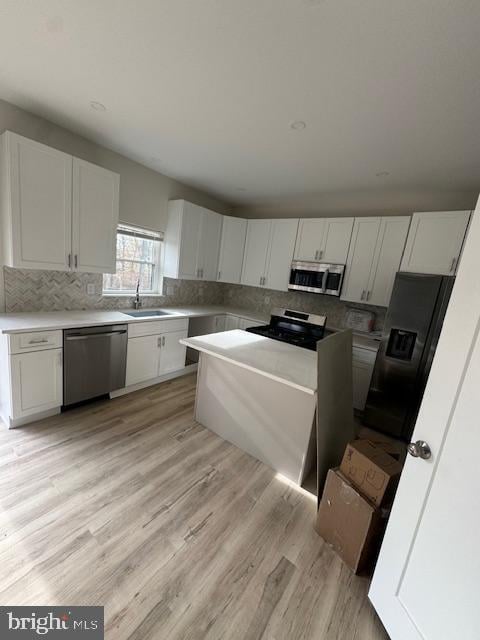 kitchen featuring sink, white cabinetry, stainless steel appliances, and light hardwood / wood-style flooring