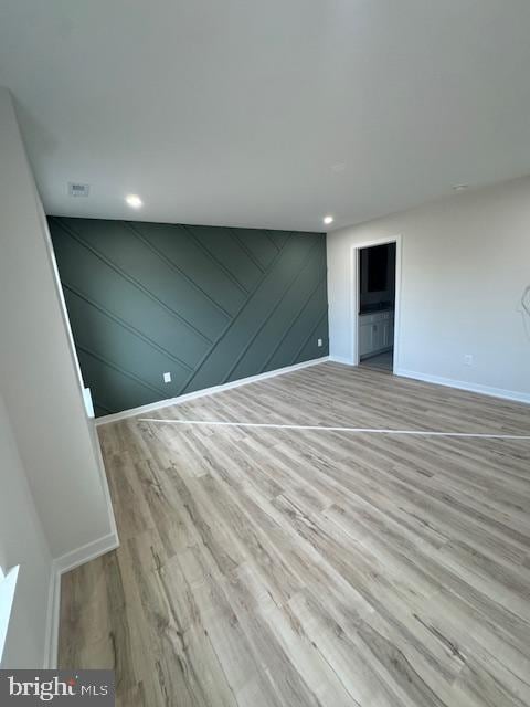 unfurnished room featuring light wood-type flooring and wood walls