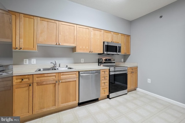 kitchen featuring appliances with stainless steel finishes, light brown cabinetry, and sink