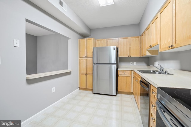 kitchen featuring a textured ceiling, light brown cabinets, sink, and appliances with stainless steel finishes