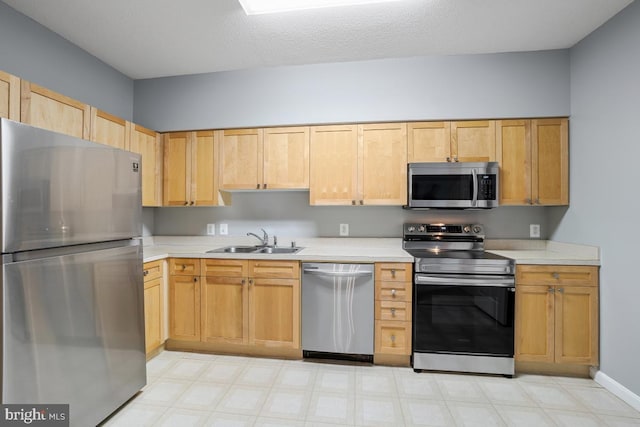 kitchen with a textured ceiling, light brown cabinets, sink, and appliances with stainless steel finishes