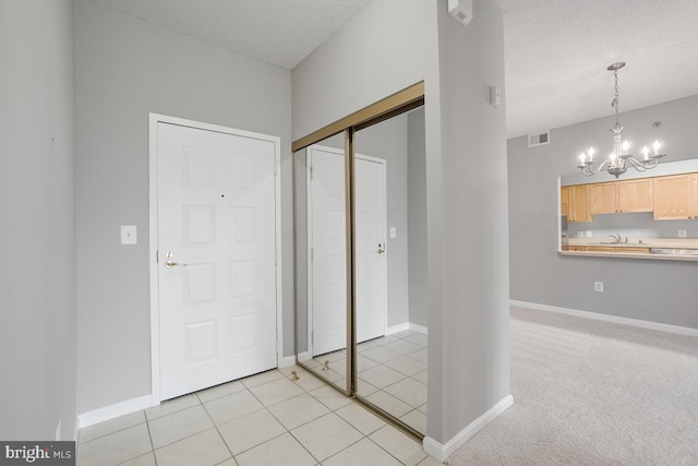 carpeted foyer with a textured ceiling, an inviting chandelier, and sink