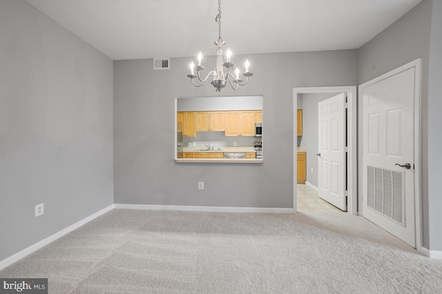 spare room with light carpet and an inviting chandelier