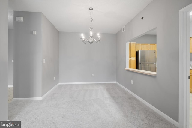 carpeted empty room featuring a chandelier