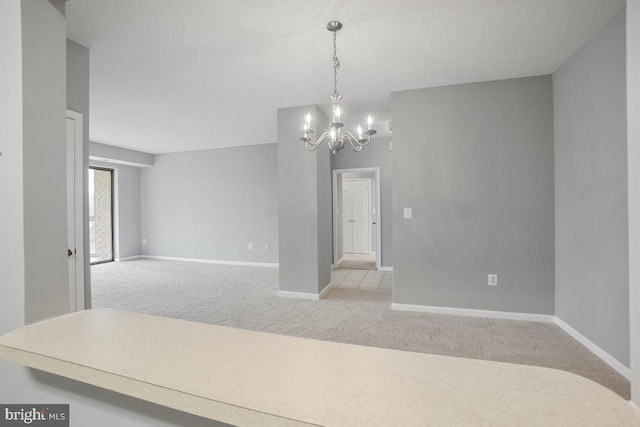 spare room featuring light carpet and a chandelier