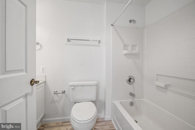 bathroom with hardwood / wood-style floors, tiled shower / bath combo, and toilet