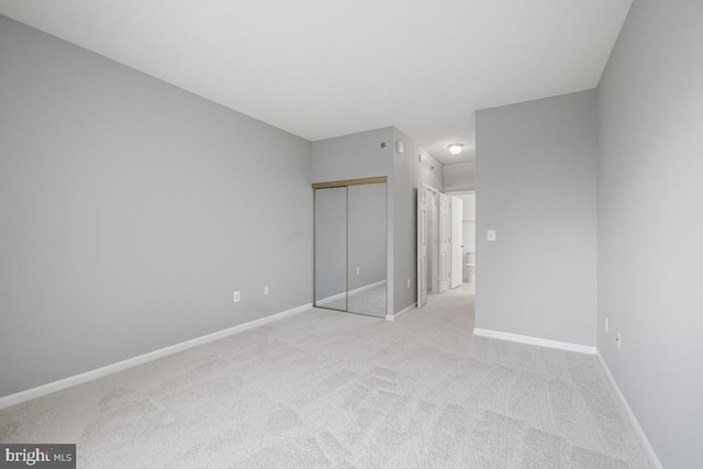 unfurnished bedroom with light colored carpet and a closet