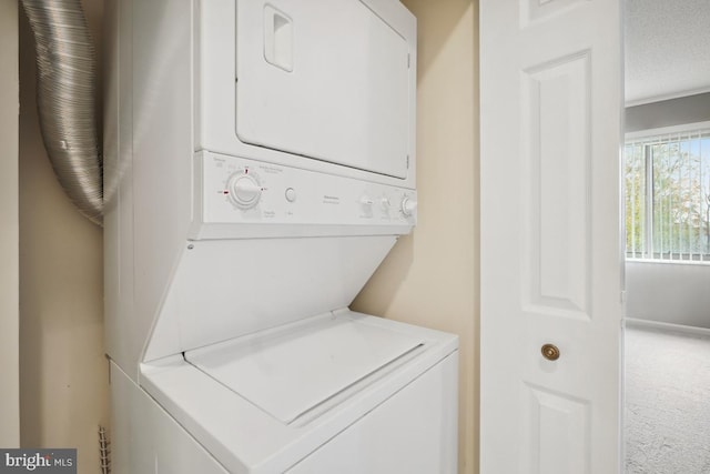 laundry room featuring carpet flooring, a textured ceiling, and stacked washer and clothes dryer