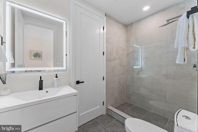 bathroom with tiled shower, tile patterned floors, vanity, and toilet