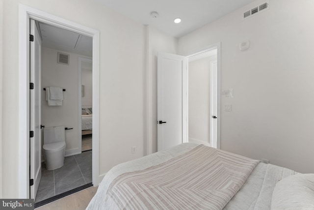 bedroom with light wood-type flooring and ensuite bath