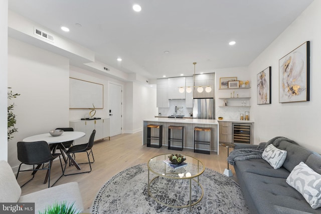 living room featuring wet bar, light hardwood / wood-style flooring, and beverage cooler