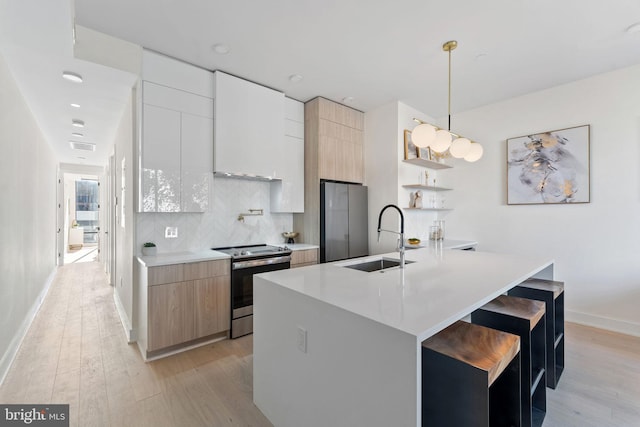 kitchen featuring sink, hanging light fixtures, light hardwood / wood-style flooring, decorative backsplash, and stainless steel appliances