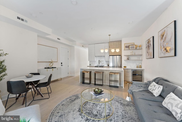 living room featuring light hardwood / wood-style floors, sink, and wine cooler