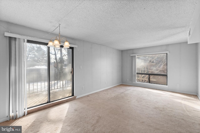 empty room featuring carpet flooring, a notable chandelier, and a textured ceiling