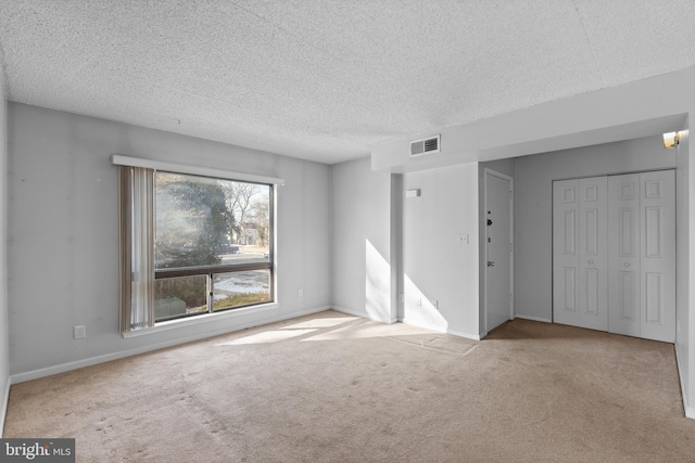 unfurnished room with light colored carpet and a textured ceiling