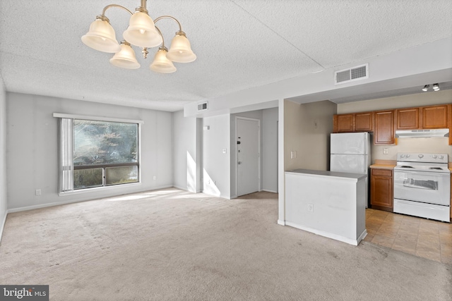 kitchen with light carpet, hanging light fixtures, white appliances, and a textured ceiling