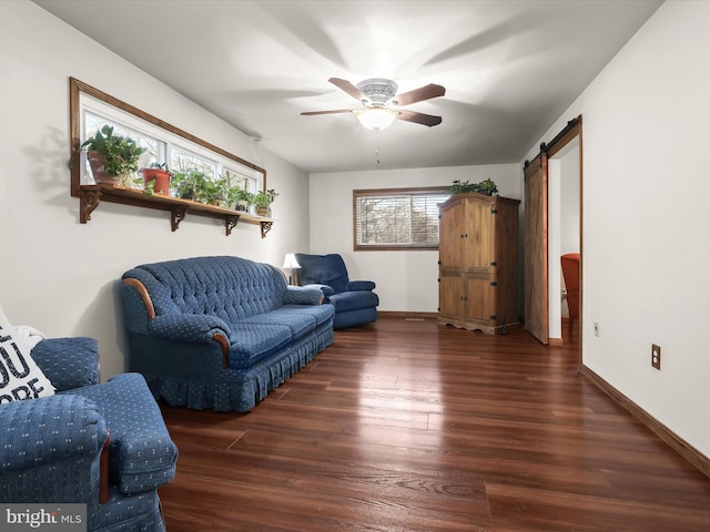 living room with dark hardwood / wood-style flooring, a barn door, and ceiling fan