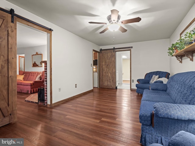 living room with ceiling fan, a barn door, and dark hardwood / wood-style flooring