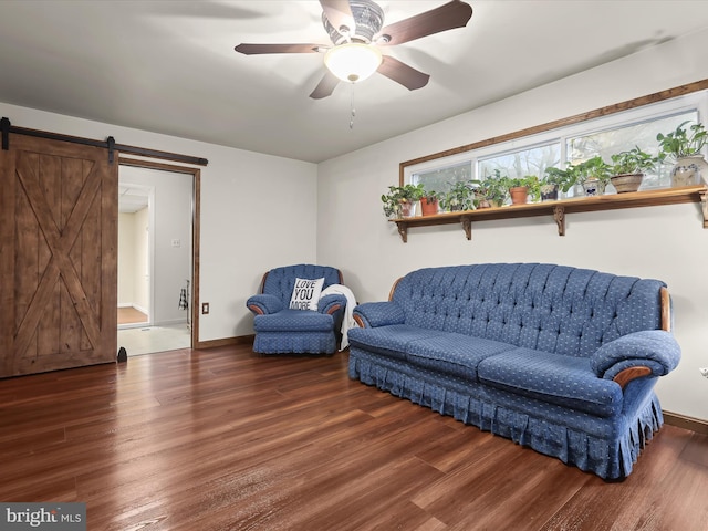 sitting room with dark hardwood / wood-style flooring, a barn door, and ceiling fan