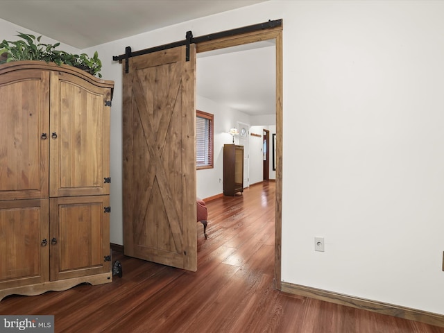 hallway with a barn door and dark hardwood / wood-style flooring