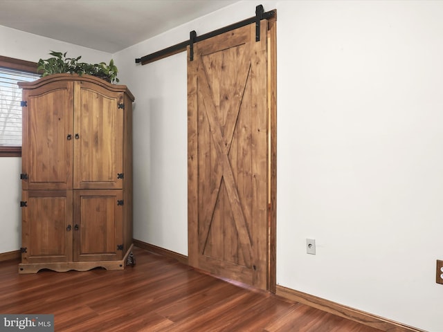 room details featuring a barn door and hardwood / wood-style flooring