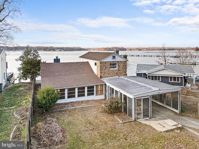 back of property featuring a sunroom and a water view