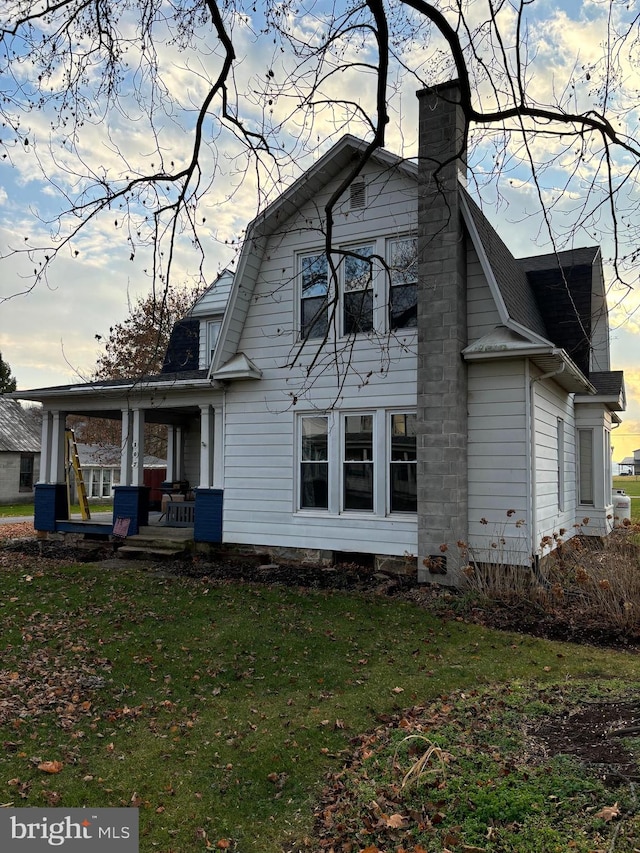 rear view of house featuring a lawn and a porch