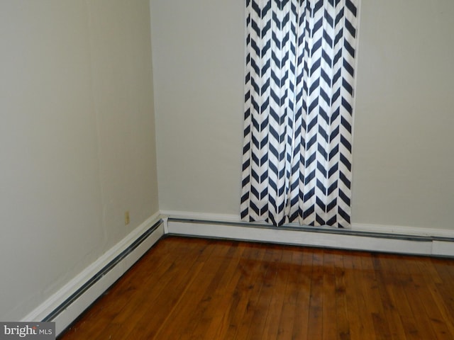 unfurnished room featuring dark hardwood / wood-style flooring and a baseboard heating unit