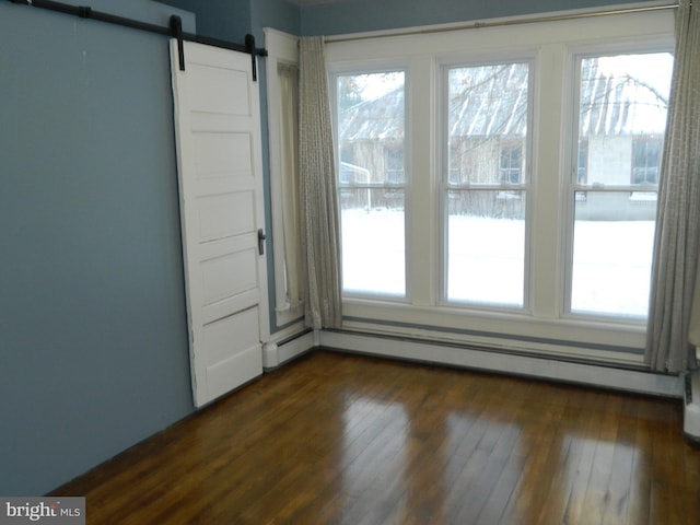 unfurnished room with a barn door, dark wood-type flooring, and a baseboard radiator