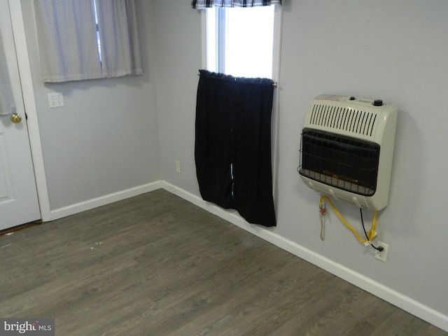 spare room featuring dark wood-type flooring and heating unit