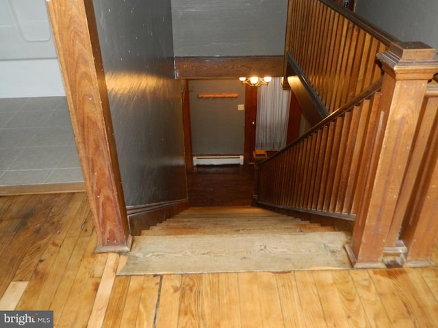 stairway with baseboard heating and hardwood / wood-style floors