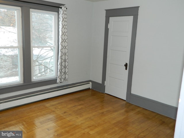 unfurnished room with hardwood / wood-style floors and a baseboard radiator