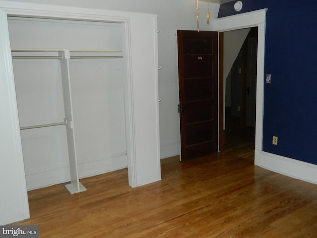 unfurnished bedroom featuring a closet and hardwood / wood-style flooring